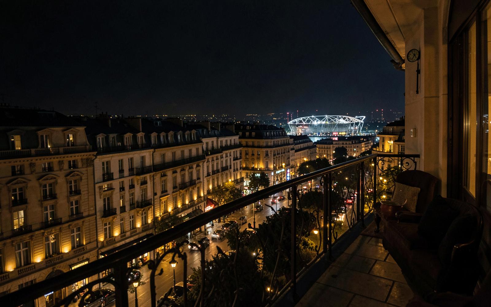 Balcony view over a floodlit stadium in a European city at night